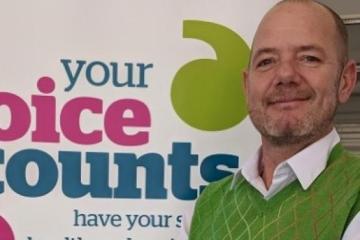 man next to healthwatch banner