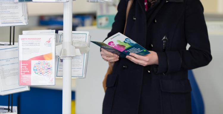 A lady looking at leaflets from a leaflet stand