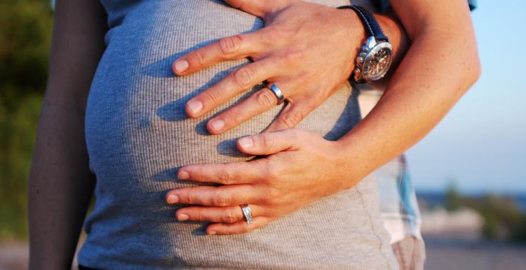 Pictire of a stethoscope held to a heavily pregnant womans stomach