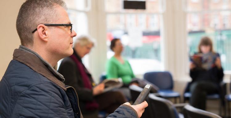 Man sat in a chair in a health centre waiting room