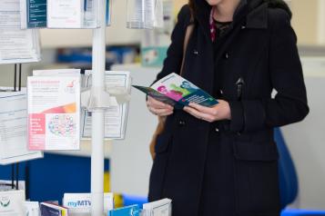 A lady looking at leaflets from a leaflet stand