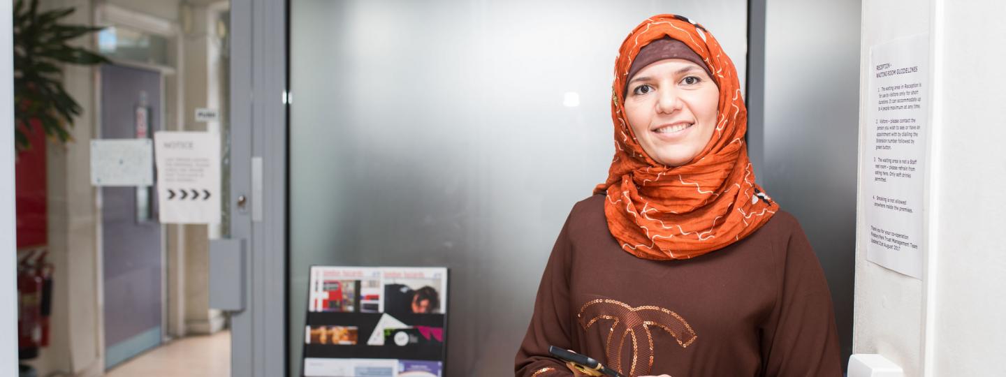 woman wearing a headscarf holding her mobile phone