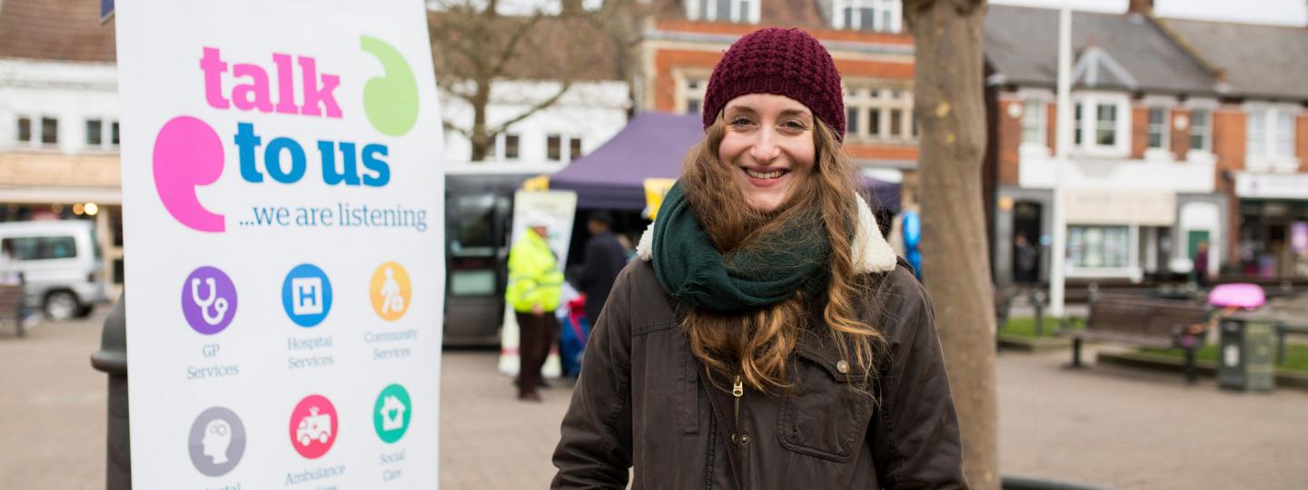 Student volunteer standing infront of a Healthwatch banner